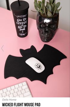 a pink desk with a computer keyboard, mouse pad and a cup filled with coffee