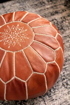 a brown leather poufce sitting on top of a rug next to a wooden table