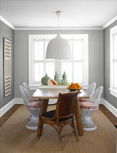 a dining room table with chairs around it and vases on the wall behind it