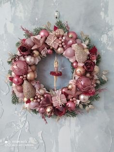 a christmas wreath hanging on the wall with ornaments around it and a cross in the center