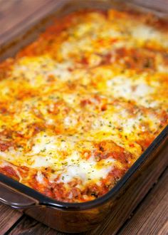 a casserole dish with meat and cheese in it sitting on a wooden table