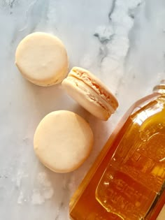 two macaroni and cheese sandwiches sitting next to a bottle of honey on a marble surface