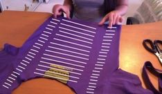 a woman is cutting out strips of purple material with scissors on the table next to her