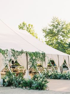 an outdoor wedding tent with greenery and candles