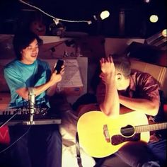 two people sitting in a room with guitars