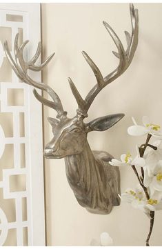 a deer head mounted to the side of a wall next to a vase with flowers