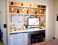 a desk with a computer on top of it and lots of wicker baskets above