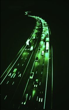 an overhead view of traffic at night with green lights on the side of the road