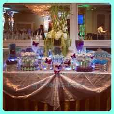 the table is set up with blue and white desserts, candy bars, and flowers