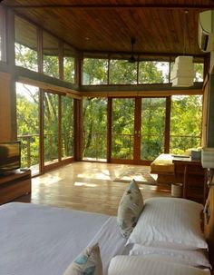 two beds in a room with windows and wood flooring next to each other on a cell phone