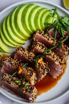 some food is on a white plate next to sliced avocado