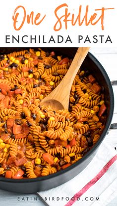 a skillet filled with pasta and beans on top of a wooden spoon next to a napkin