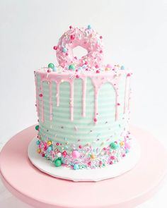 a pink and white cake with sprinkles on it sitting on a table