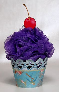 a cupcake with purple icing and a cherry on top, sitting in front of a white background