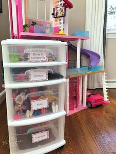 three plastic bins filled with toys on top of a wooden floor next to a window