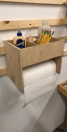 a toilet paper holder with pencils, markers and other items in it on a shelf