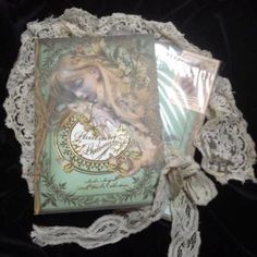 an open book with lace on it and a ribbon tied around the cover, sitting on top of a doily