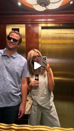 a man and woman taking a selfie in front of an elevator with their cell phone