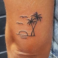 a small palm tree tattoo on the back of a man's left arm