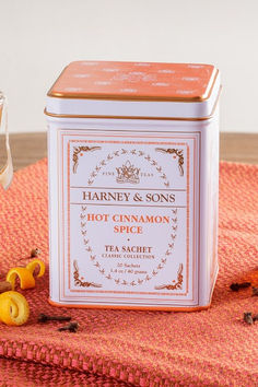 a tin of hot cinnamon spice sitting on top of a table next to some orange peels