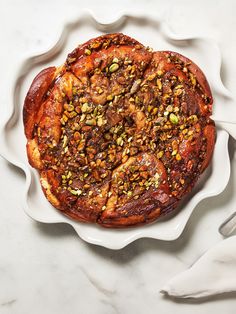 a white plate topped with a pastry covered in nuts