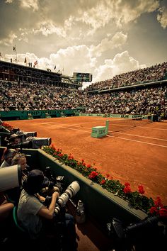 the tennis court is full of spectators and people watching it from their seats in front of them