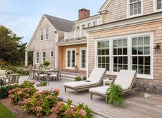 an outdoor deck with chaise lounges and flowers on the ground next to it