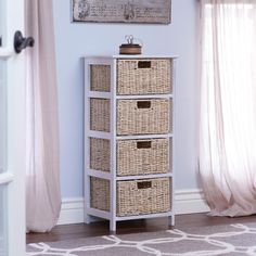 a white dresser with wicker baskets on it in front of a painting and window