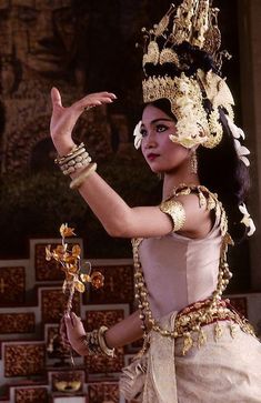 a woman dressed in traditional thai garb and holding a cross on her left hand