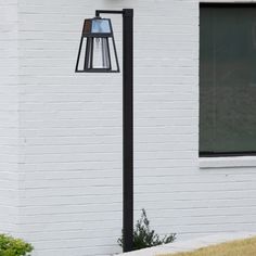 a black lamp on the side of a white brick building in front of a window