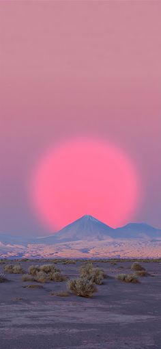 the sun is setting over mountains in the distance, with pink sky and purple clouds