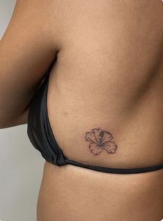 a woman's stomach with a flower tattoo on her left side ribcage