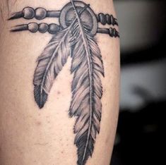 a black and white photo of a feather with beads on it's side tattoo