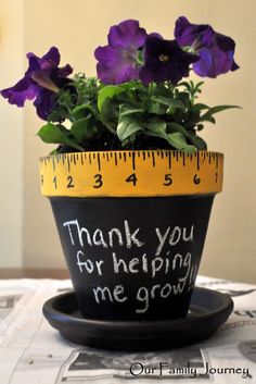 a potted plant with purple pansies in it and a measuring tape on top