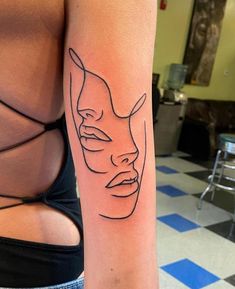 a woman's arm with a tattoo on it that has a line drawing of a mask