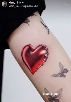 a woman's arm with a red heart tattoo on it