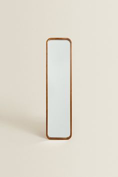 a wooden mirror sitting on top of a white wall