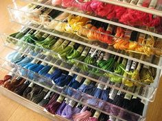 several rows of spools of thread in plastic containers on a wooden table top