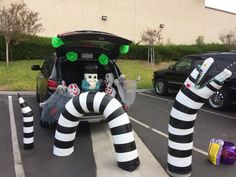 the trunk of a car is decorated with fake black and white striped legs, while two people are sitting in the back