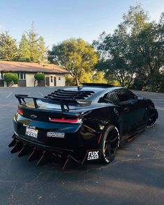 the rear end of a black sports car with spikes on it's tailpipes