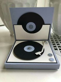 an open record player sitting on top of a white table next to a black and silver object