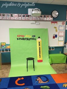 an image of a classroom setting with a green screen and black chair on the floor