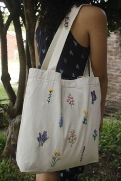 a woman carrying a white bag with flowers on it