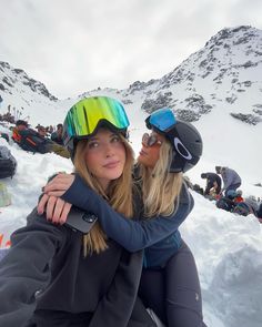 two women sitting in the snow hugging each other