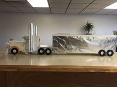 a toy truck is covered in tinfoil on top of a table with a potted plant