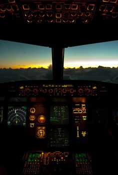 the view from inside an airplane cockpit at sunset or dawn, looking out over clouds