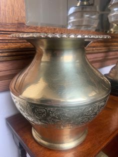 a silver vase sitting on top of a wooden table