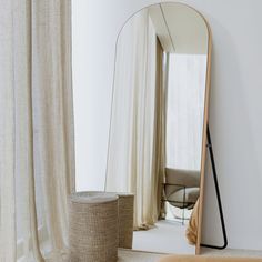 a large mirror sitting on top of a white floor next to a table and chair