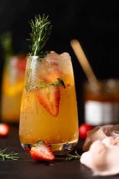 a drink with strawberries and rosemary garnish in a glass on a table