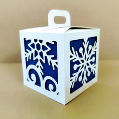 a white box with blue snowflakes cut out of it sitting on a table